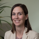 A woman with brown hair and a jacket smiles for the camera.