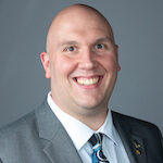 A man in a suit and tie smiling for the camera.