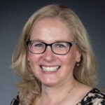 A woman with glasses smiling for the camera.