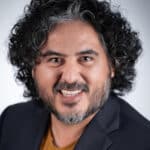 Smiling man headshot with curly hair and beard