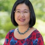 Smiling woman wearing glasses, floral blouse, necklace